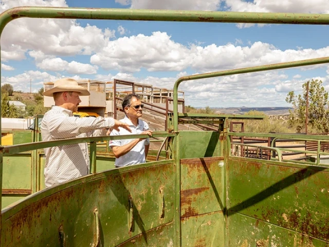Two men examine agricultural equipment at a ranch.