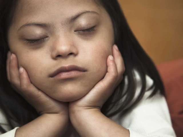 a girl with her eyes closed with her chin resting in her hands